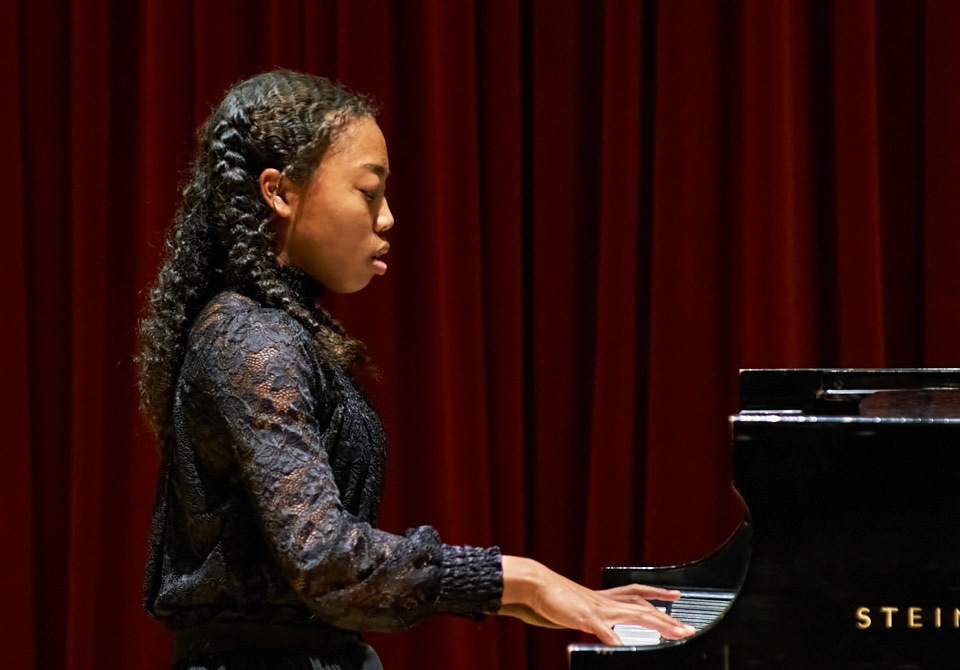 A young woman plays piano